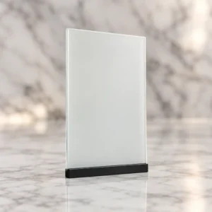 Campione di vetro con film PDLC SF97 White Adhesive bianco opaco, su base nera e sfondo in marmo chiaro.